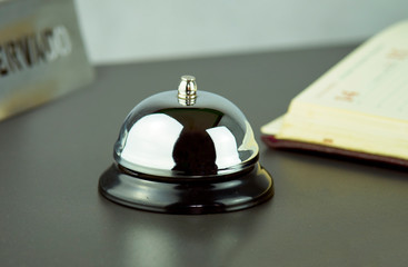 Service bell on a black desk with a reservation book 