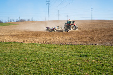 Farmer plowing the field. Cultivating tractor in the field. Red farm tractor with a plow in a farm field. Tractor and Plow