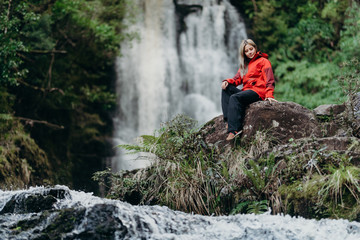 Obraz premium Beautiful woman hiker standing at front of waterfalls and looking away. Asian female on hike in nature.
