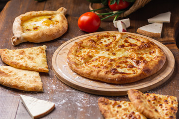 Caucasian Georgian kitchen. Bakery products. Pie with cheese. Set from khachapuri, Imeretian, Megrelian and Adjarian. On the wooden table.