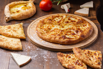 Caucasian Georgian kitchen. Bakery products. Pie with cheese. Set from khachapuri, Imeretian, Megrelian and Adjarian. On the wooden table.