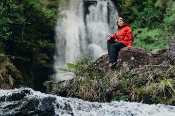 Obraz premium Beautiful woman hiker standing at front of waterfalls and looking away. Asian female on hike in nature.