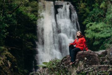 Obraz premium Beautiful woman hiker standing at front of waterfalls and looking away. Asian female on hike in nature.