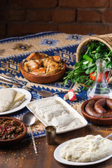 The table dishes set of Georgian cuisine, lots of delicious food, vodka, greens, vegetables and roasted meat
