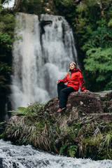 Obraz premium Beautiful woman hiker standing at front of waterfalls and looking away. Asian female on hike in nature.