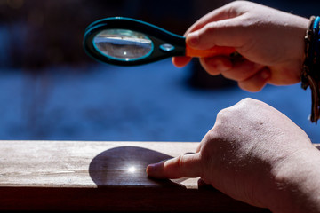 a magnifying glass in the hands of a man who teaches a child to make a fire with a magnifying glass