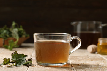 tisana o infuso di ortica  in bicchiere su sfondo rustico 