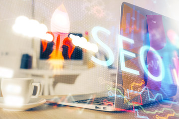 Double exposure of table with computer and seo drawing hologram. Search optimization concept.