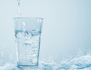 volles wasserglas mit wasserstrahl steht in der sprudelnden wasserquelle, konzept für klares frisches trinkwasser