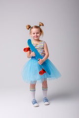 portrait of a little blonde girl smiling holding a skate Board on a white background