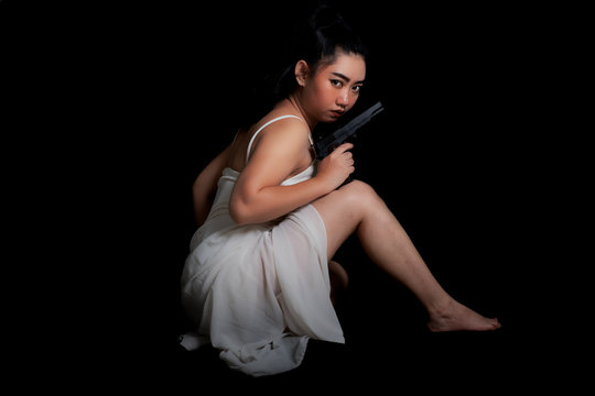 Portrait beautiful Asia woman one hand holding gun at the black background, Young sexy girl long hair with a handgun, Pretty women stand with a pistol, look at camera