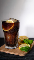 Cubalibre. glass of cola and rum with ice, mint and lemon on wooden table and a white background. 