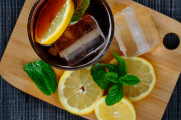 Cubalibre. glass of cola and rum with ice, mint and lemon on wooden table. View from above.