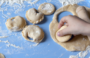Dumplings with flour in hand on blue background. Traditional dish of ukrainian cuisine