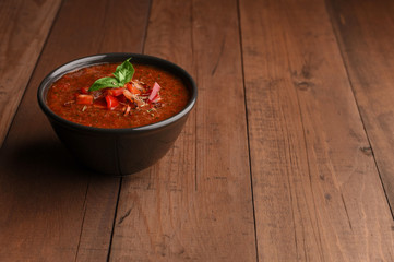 Spicy Homemade Gazpacho Soup with basil on wood table. Summer tomatoes cold soup in bowl with place for text. Copy space. 
