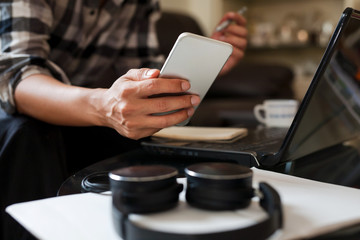 a businessman working from home holding a smartphone to checking dairy planning to prepare meeting with a team by video conference on laptop at home office.