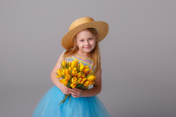 a little girl in a straw hat holding a yellow flower