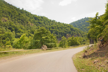 Mountain road between forests . Winding mountain road . A road in Azerbaijan between Forest . Empty road in mountainous area along mountains . highway and mountain with beautiful clouds landscape.