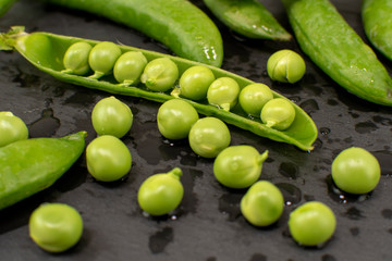 Raw young green peas and pods peas on grey background, selective focus.