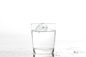 Glass with water and ice on a white background. Glass of mineral water and ice on white background.