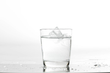 Glass with water and ice on a white background. Glass of mineral water and ice on white background.