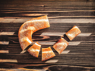 sliced baguette with sesame seeds on dark boards. light through the blinds