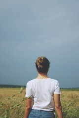 A blonde girl in white t-shirt and jeans standing in the field