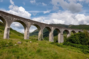 Fototapeta na wymiar The landscape with famous Glenfinnan Viaduct in Scotland in perspective view from bottom with blue sky and clouds