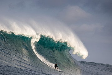 Surfer riding massive wave