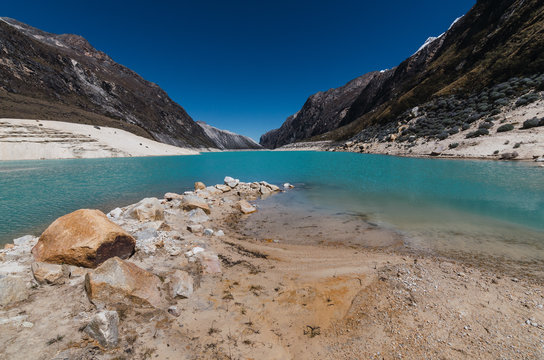 rocks and sand in the turquoise lagoon of paron surrounded by mountains, peru