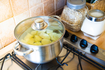 Boiling potatoes in the pot with cover in kitchen