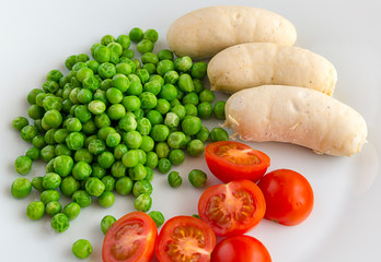turkey sausages garnished with poached green peas and tomatoes
