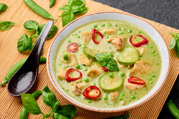 Thai Green Curry with Chicken or Gaeng Kaew Wan Gai in white bowl at black slate background. Thai Green Curry is a Thailand cuisine dish with green chillies, basil, coconut milk, vegetables and spices