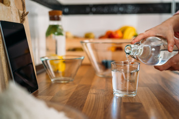 Woman's Hands pouring water into a glass in her home kitchen