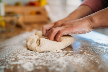 Woman kneading the dough to make a pizza in her home kitchen