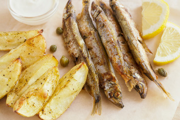 fried capelins, wedges, sauce, and lemon