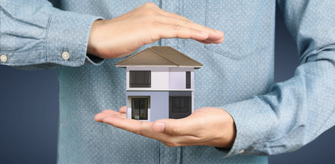 Mortgage concept by money house. holding  house model in hand