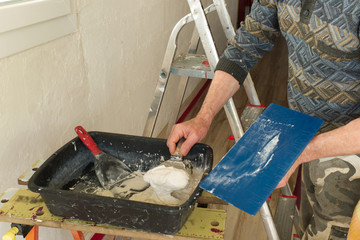Dépose d'enduit, de plâtre sur un mur par un plâtrier et préparation du mélange dans une auge...