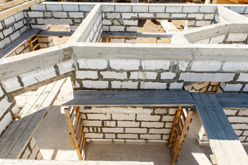 Building site of a house under construction. Unfinished house walls made from white aerated autoclaved concrete blocks. Scaffolding for workers assembled from boards and Euro-pallets. top view