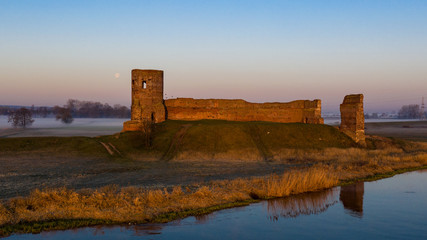Ruiny zamku w Kole z drona o wschodzie słońca nad Wartą we mgle - obrazy, fototapety, plakaty