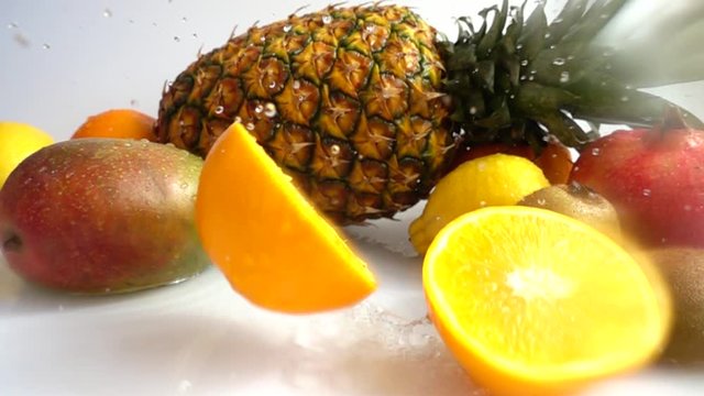 Fall of orange against the background of tropical fruits. Slow motion.