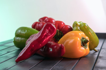 Freshly picked sweet peppers of different varieties. Ripe peppers on a dark wooden table.