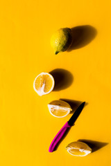 Lemons on a yellow background with pink knife 