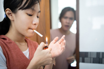 Child girl light up the cigarette at home,woman secretly smoking the cigarette in the...