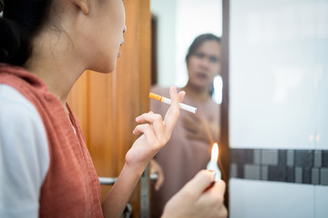 Teenager girl light up the cigarette at home,woman secretly smoking the cigarette in the...