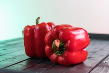 Red bell peppers on a dark wooden table. Still life in the style of minimalism with pepper. Vegetarian still life. Fresh vegetables on dark boards.