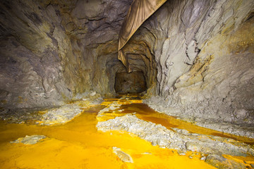 Abandoned copper ore mine underground tunnel with yellow dirt