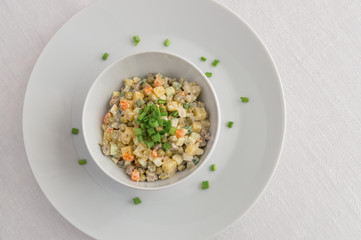 olivier salad dressed with mayonnaise and decorated with green onion