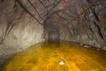 Abandoned copper ore mine underground tunnel with yellow water