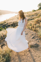 Bride in a luxurious white wedding dress in nature at sunset